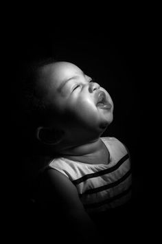 a black and white photo of a young child with his mouth open in the dark