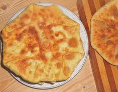 two pizzas sitting on top of a wooden cutting board