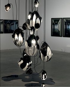 an art installation consisting of black and white balls hanging from the ceiling, with multiple frames on the wall