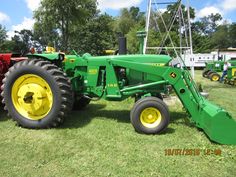 a green tractor parked on top of a lush green field