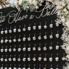 a black and white wedding sign with lots of earrings on it's side, surrounded by flowers