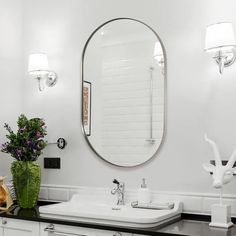 a bathroom with two sinks and a large round mirror