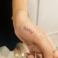 a woman's left hand with the word evil tattooed on her right thumb and wrist