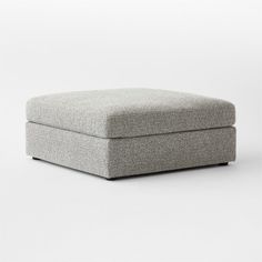 a grey ottoman sitting on top of a white floor