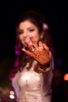 a woman is holding her hand up to show the henna on her palm and smiling