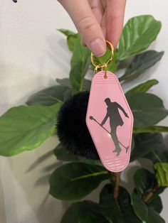 a pink keychain with a black silhouette of a person holding a tennis racket