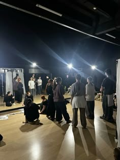 a group of people standing on top of a wooden floor next to each other in front of a mirror