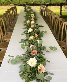 a long table with flowers and greenery on it