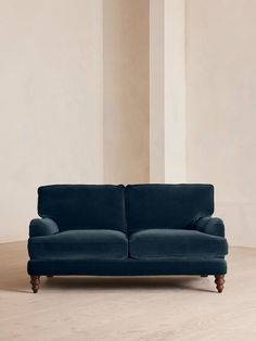 a blue couch sitting on top of a hard wood floor next to a white wall