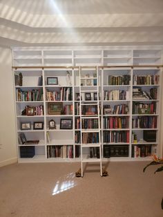 a white book shelf filled with lots of books next to a wall full of shelves