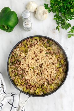 a skillet filled with rice and vegetables on top of a counter next to garlic