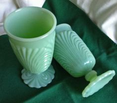 two green glass cups sitting on top of a bed