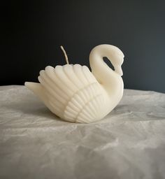 a white swan shaped candle sitting on top of a table