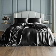 a bed with black sheets and pillows on top of it in a room that has wood floors