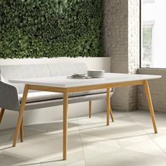 a living room with a couch and table in front of a wall that has green plants on it