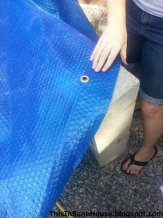 a woman standing next to a blue tarp with her hand on the top of it