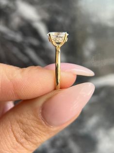 a woman's hand holding a yellow gold ring with a diamond in the middle