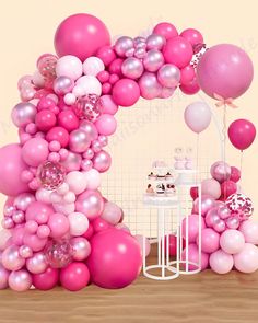 a pink and white balloon arch with balloons