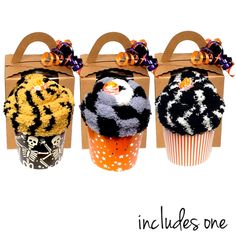 three cupcakes decorated with black, white and orange icing in front of a cardboard bag