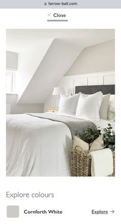 a bed with white linens and pillows in a small room next to a window