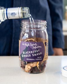 a glass jar filled with blackberries and ginger smash sitting on top of a counter