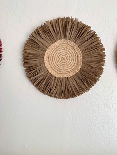 three woven baskets hanging on the wall with different colors and shapes in them, one is made from straw