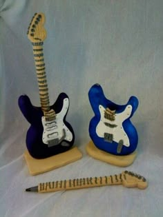 two blue and white electric guitars are next to a pencil holder with a guitar on it