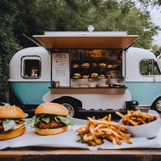 a food truck with two hamburgers and french fries on the table next to it