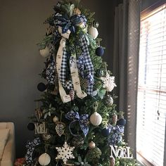 a christmas tree decorated with blue and white ribbon, ornaments and snowflakes