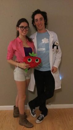 a man and woman standing next to each other in front of a wall with an apple on it