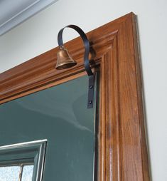 a bell hanging from the side of a wooden door with a mirror in front of it