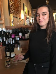 a woman standing in front of bottles of wine