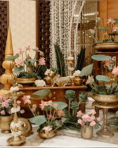 a table topped with lots of potted plants and vases filled with pink flowers