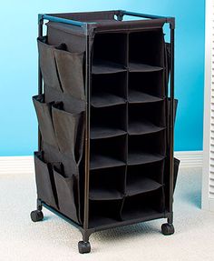 a black rolling storage unit with six bins on wheels in front of a blue wall