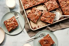 a pan filled with brownies next to cups and saucers on top of a table