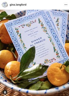 a bowl filled with oranges on top of a table next to a menu card