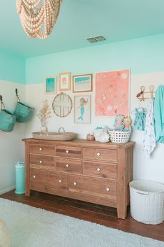 a baby's room with a dresser and pictures on the wall