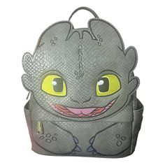 a small gray backpack with yellow eyes and an adorable creature on the front, sitting in front of a white background