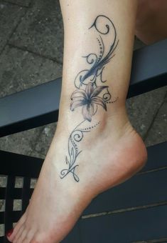 a woman's foot with a flower tattoo on the side of her left leg