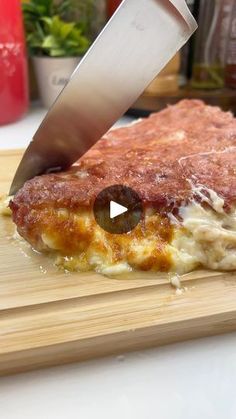 a person cutting up food on top of a wooden cutting board with a large knife