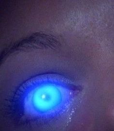 a close up of a person's eye with glowing blue eyes