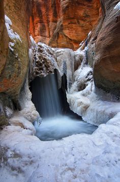 a small waterfall in the middle of a snowy canyon