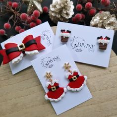 three pairs of santa claus earrings on top of white cards with red and black bows