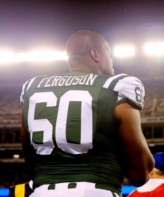 a close up of a person wearing a football uniform on a field with lights in the background