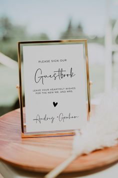 a sign that is on top of a wooden table next to a white and black feather