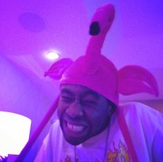 a man wearing a pink flamingo hat and smiling