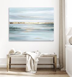 a painting hanging on the wall above a bench in a room with white walls and wooden flooring