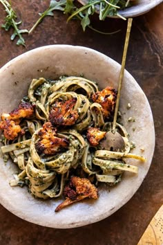 a bowl filled with pesto pasta and topped with parmesan bread croutons