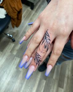 a woman's hand with blue and purple nail polishes on her fingers, while she is wearing a ring