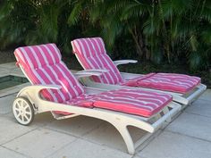 two lawn chairs with pink and white striped cushions are sitting in front of a swimming pool